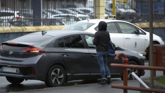 Un taxi circula al lado de un VTC por el que espera una usuaria en A Coruña, en una imagen de archivo.