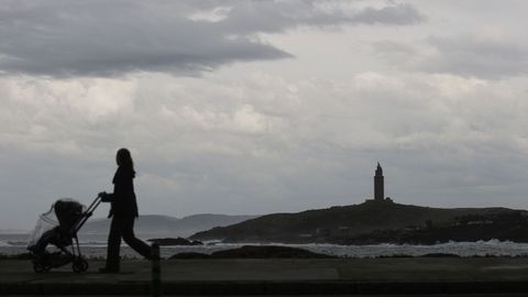 Una mujer camina por el paseo mar�timo de A Coru�a en una jornada lluviosa.