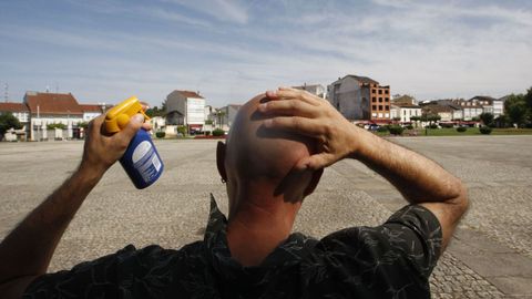 Un hombre se aplica crema protectora en la cabeza en la plaza de la Compañía en Monforte.
