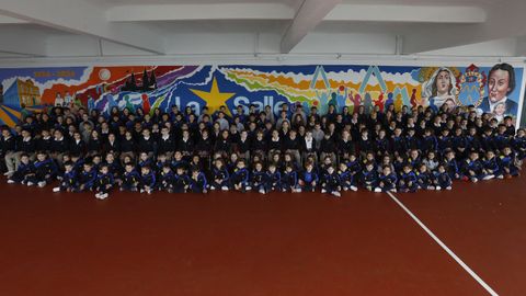 Foto de familia del alumnado de infantil y primaria delante de un mural que conmemora el centenario