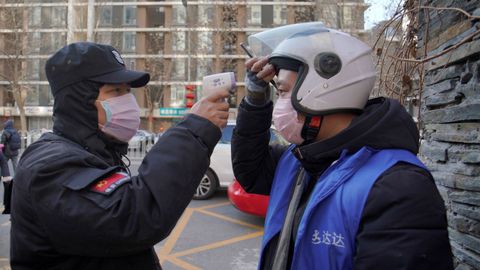 Un empleado de seguridad toma la temperatura a un ciudadano chino en Pek�n. La capital ha establecido controles de salud en el metro y el tren