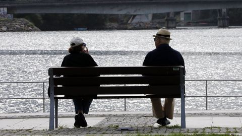 Dos jubilados descansan en un banco en un parque de Viveiro