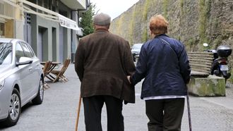 Un matrimonio de personas mayores caminando de la mano.