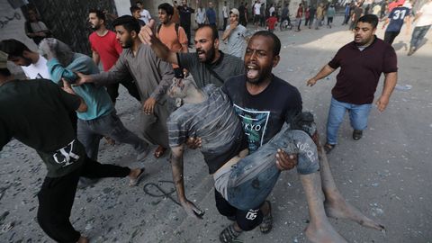 Un gazat� huye de la destrucci�n causada por los bombardeos israel�es portando a otro en brazos que result� herido