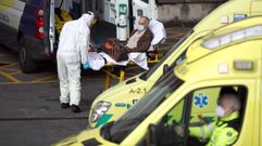 Un trabajador de ambulancias con los epis lleva a un paciente de covid al hospital vizca�no de Cruces.