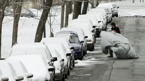 Un hombre retira la lona de su coche.