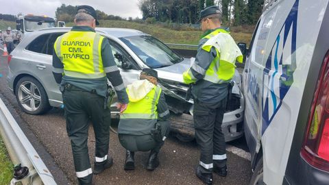 Tres agentes de Tráfico de la Guardia Civil inspeccionan dos de los vehículos implicados.