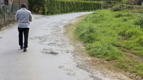 Un residente camina al lado de los numerosos baches en el lateral de la calzada. 