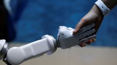 Charlermpon Punnotock, director general de CT Asia Rob�tica da una mano a un robot en Bangkok (Tailandia)