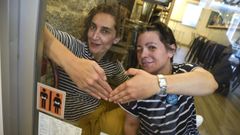 María Mariño y Marisol Fernández, con la pegatina del proyecto «Preciso pasar» que exhibe el Tábula Rara de Pontevedra, el primer local en sumarse a la iniciativa