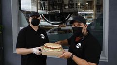 Nicol�s Orrego (en la foto, a la derecha) muestra junto a John, al que contrat� a ra�z de la apertura de la bocater�a Migas, uno de sus bocadillos en pan de aceite (de 22 cent�metros de di�metro). El negocio,  situado en la esquina entre las r�as Viorneira y Rosal�a de Castro, ofrece servicio a domicilio y de �take away� (para recoger en el local)