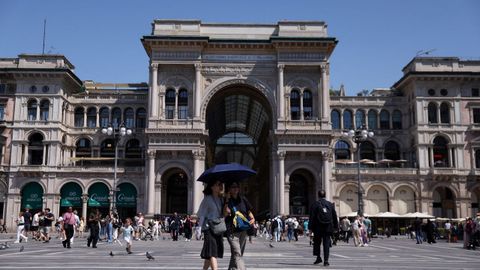 Varias personas se protegen del sol con un paraguas junto a la Galer�a Vittorio Emanuele II de Mil�n (Italia).