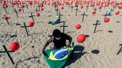 Un hombre instala una bandera de Brasil en una representaci�n esc�nica de la ONG R�o de Paz por las 100.000 v�ctimas mortales del covid en el pa�s