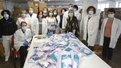 Los encargados de la gran compra. El servicio de suministros se estructura en dos secciones: una de compras, que cuenta con doce personas y otra de almac�n, con cinco, (en la foto de grupo alrededor de la mesa con los kits de supervivencia para los sanitarios, en el centro los responsables Loli Mari�as, de negro, y Fran Romalde, detr�s). Los trabajadores se turnan para trabajar desde casa desde que comenz� la pandemia.