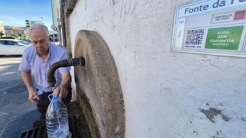 Un hombre cog�a agua este domingo en la conocida como fuente de Fenosa, en Teis, con un cartel que dice que no tiene garant�as