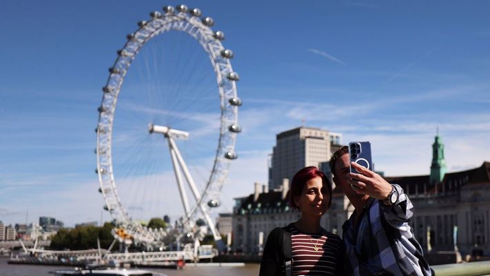 Dos turistas se hacen un selfie en el centro de Londres, con la noria London Eye de fondo.