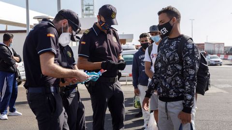 Unos policas revisan los papeles de unos inmigrantes trasladados desde Gran Canaria a Tenerife para ser alojados en un hotel del sur de la isla gracias a la gestion de la Cruz Roja