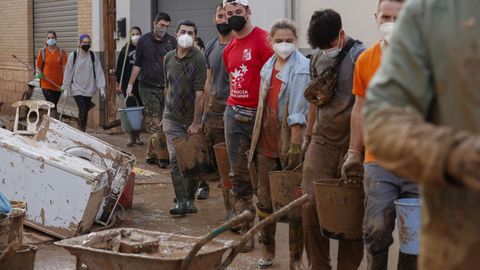 Un grupo de jóvenes forma una cadena para cargar cubos en Paiporta