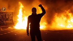 Uno de los manifestantes, con el rostro oculto bajo una m�scara, ante una de las barricadas en llamas