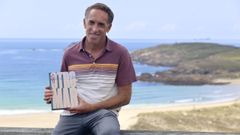 Jes�s Busto, con su libro en la playa de Doni�os, donde el autor surfea a diario y tiene su hogar