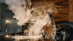 Una mujer joven entre el humo generado por un vapeador