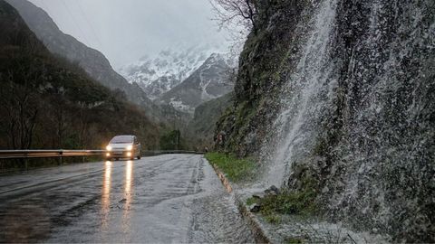 Un coche circula por una carretera mojada en Asturias.