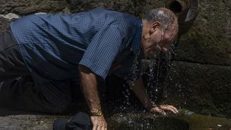 Un hombre se refresca en una fuente de Santiago
