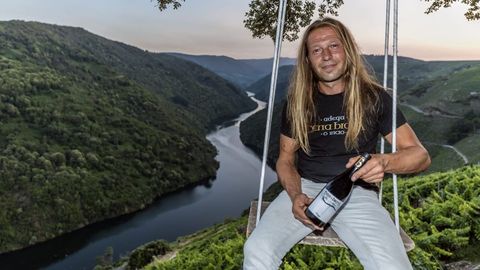 Breogn Pereiro con una de las botellas de la bodega, sentado en el columpio