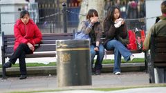 Unas j�venes toman un bocadillo sentadas en un banco.