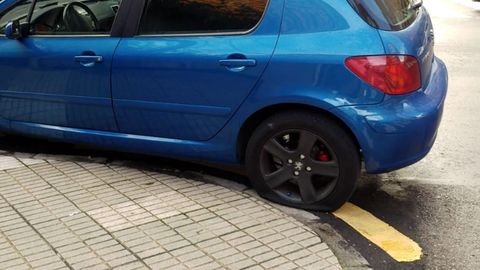 Un autom�vil con una de las ruedas pinchadas, en el barrio de El Natahoyo de Gij�n