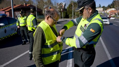 Un guardia civil de Tr�fico coloca un chaleco reflectante a un peat�n en A Coru�a.