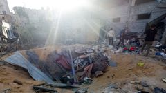 Varios palestinos inspeccionan el lugar donde un misil israel� impact� contra una vivienda, en Rafah