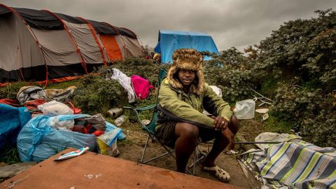 Un hombre sentado en una silla plegable en el campamento de inmigrantes de Calais, conocido como Nueva Jungla, donde muchos tratan de llegar a Inglaterra.