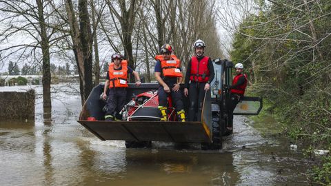 Un granjero transporta a un grupo de bomberos que trabajan en la zona de Co�mbra afectada por la rotura de un dique