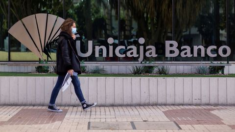 Una mujer pasa ante la sede de Unicaja en Mlaga