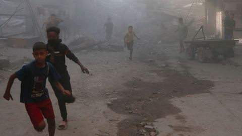 Un grupo de nios huyen entre los escombros y el polvo tras un ataque israel en la Ciudad de Gaza