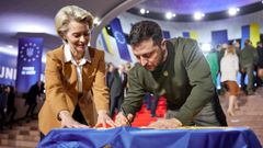 Zelenski firma una bandera ucraniana junto a Von der Leyen.