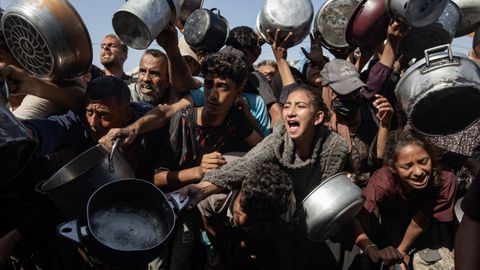 La hambruna sigue en la Franja: palestinos desplazados sostienen ollas y sartenes de metal mientras se renen para recibir comida, el viernes.