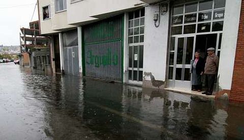 Dos vecinos observan el avance del agua durante la pleamar.