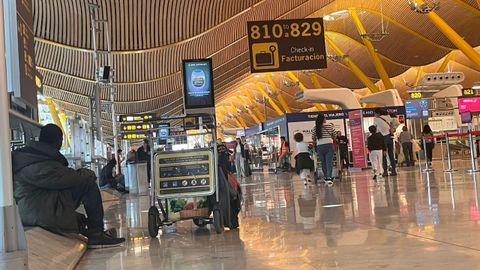 Una persona sin hogar entre los pasajeros de la T4 del Aeropuerto Adolfo Surez Madrid-Barajas.
