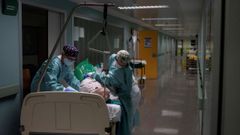 Sanitarios atienden a un paciente recuperado de coronavirus en el pasillo de la unidad de reanimaci�n (REA) del Complejo Universitario de Ourense, este mi�rcoles. Agotados pero al pie del ca��n un d�a tras otro. As� est�n en cr�ticos. No en vano, es la mejor definici�n del estado de �nimo de los profesionales sanitarios que lidian con los contagios de la covid-19, tanto desde Cuidados Intensivos (UCI) como en REA.
