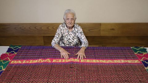 Balbina posa en su casa con una manta tejida por ella hace 73 años