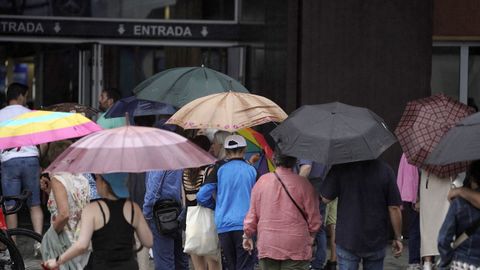  Los visitantes se protegen de la intensa lluvia esta ma�ana en la Feria