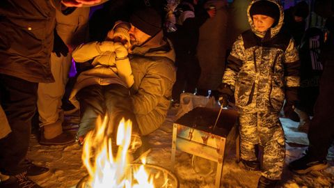 Un grupo de personas se calientan en un fuego en una calle de Kiev