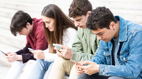 Un grupo de j�venes, consultando sus tel�fonos m�viles, en una imagen de archivo.