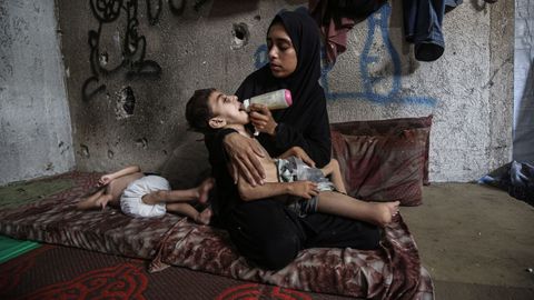 Una madre da de comer a su hijo desnutrido en un refugio de la ciudad de Gaza.
