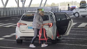Una mujer saliendo del taxi en la terminal de llegadas del aeropuerto de Lavacolla, en Santiago