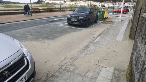 Arena acumulada junto a la acera del otro lado de la calle, y en las plazas de aparcamiento