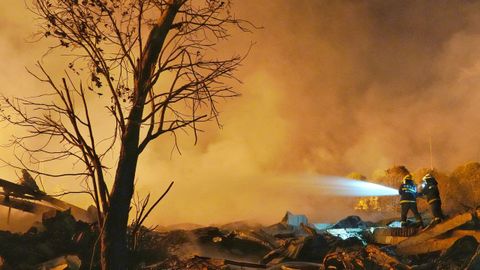 Los bomberos chinos intentando apagar el fuego en la f�brica afectada