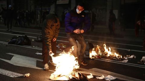 Dos personas encienden con aerosoles restos de basura tirados cerca de la Puerta del Sol de Madrid